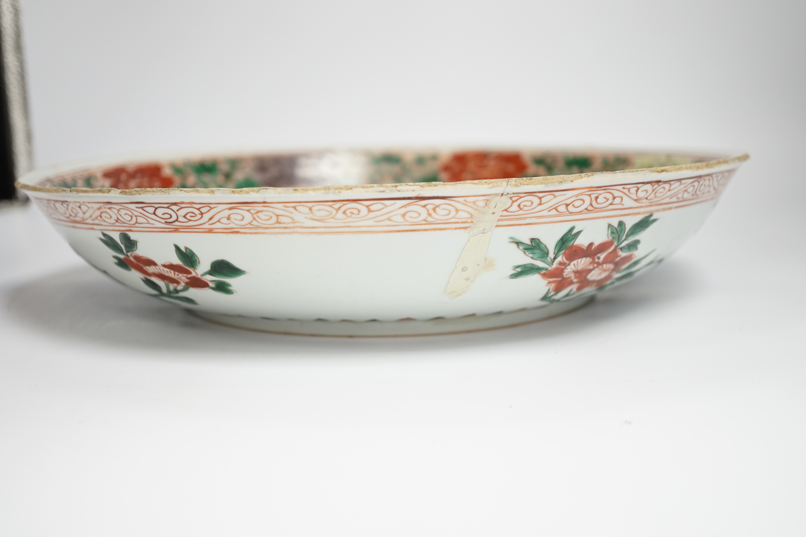 A Chinese famille verte dish, Kangxi period, decorated with flowers bands of brocade patterns, channel moulded foot, 33cm diameter